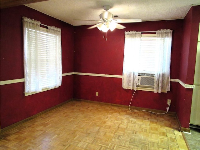 empty room with a textured ceiling, light parquet floors, ceiling fan, and a healthy amount of sunlight