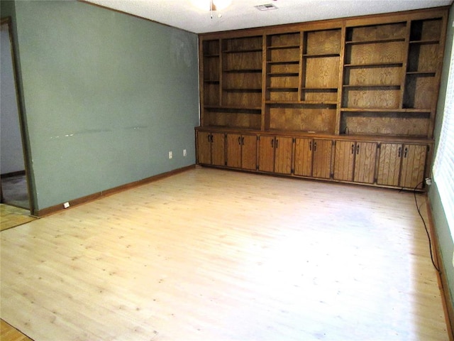 unfurnished room with light hardwood / wood-style flooring and a textured ceiling