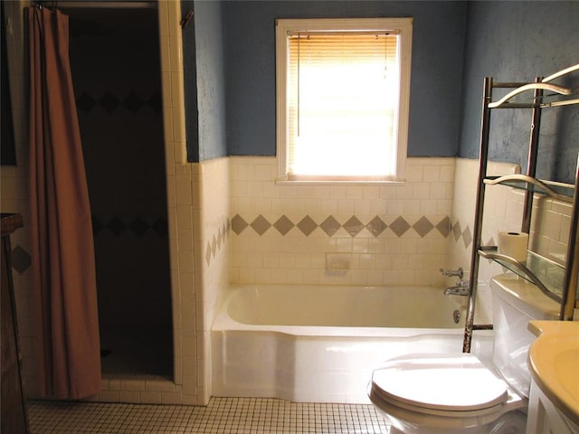 bathroom featuring tile patterned flooring, a bath, toilet, and tile walls