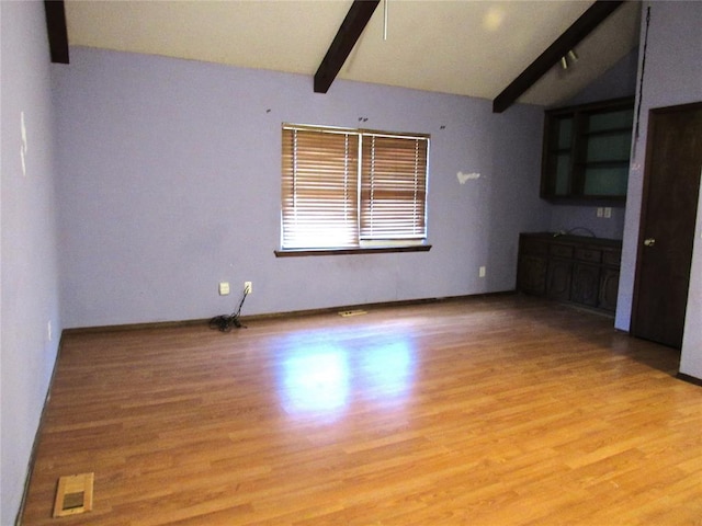 interior space with light wood-type flooring and lofted ceiling with beams