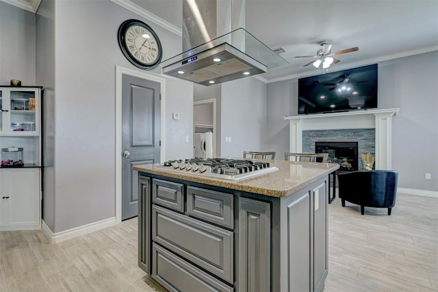 kitchen with island range hood, washer and clothes dryer, a center island, and stainless steel gas cooktop