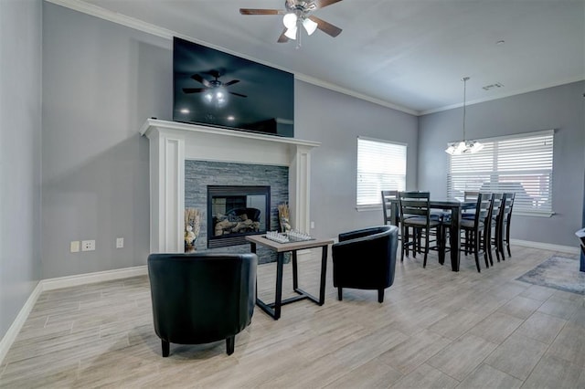 living room featuring crown molding, a fireplace, ceiling fan with notable chandelier, and light hardwood / wood-style floors