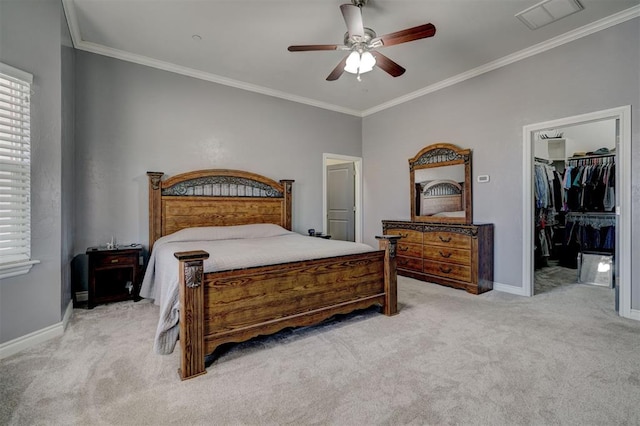 bedroom with crown molding, a walk in closet, light colored carpet, and ceiling fan