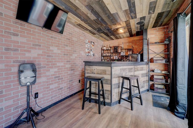 bar featuring wood ceiling, brick wall, and light hardwood / wood-style flooring