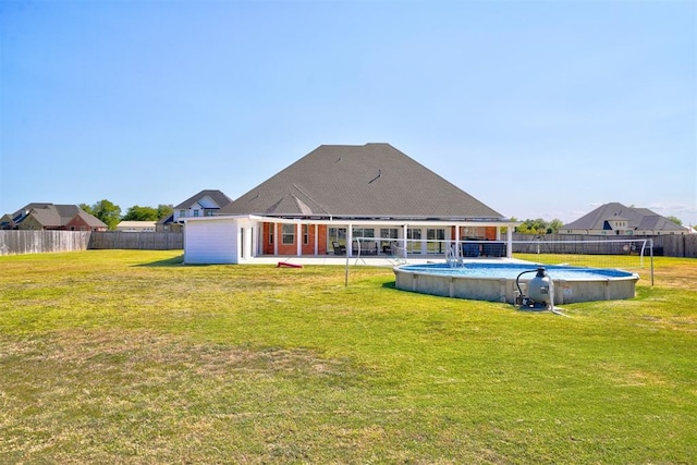 rear view of property featuring a fenced in pool and a yard