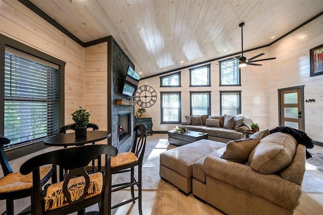 living room featuring ceiling fan, light hardwood / wood-style flooring, wooden ceiling, a stone fireplace, and lofted ceiling