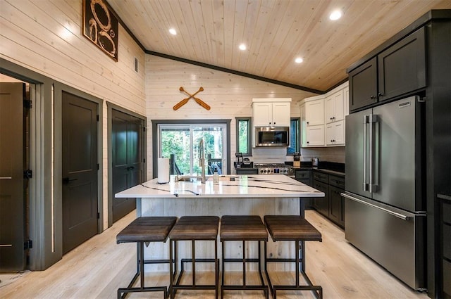 kitchen featuring white cabinetry, stainless steel appliances, a kitchen breakfast bar, high vaulted ceiling, and a kitchen island