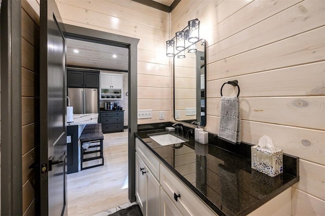 bathroom featuring wood walls, hardwood / wood-style floors, and vanity