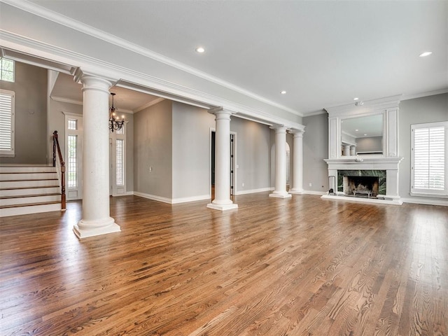 unfurnished living room with wood-type flooring, crown molding, a high end fireplace, and an inviting chandelier