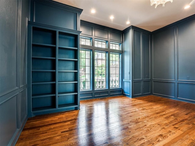 unfurnished room featuring hardwood / wood-style floors, an inviting chandelier, and built in features