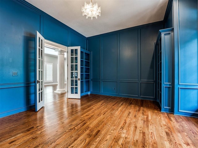 spare room featuring ornate columns, crown molding, french doors, and wood-type flooring