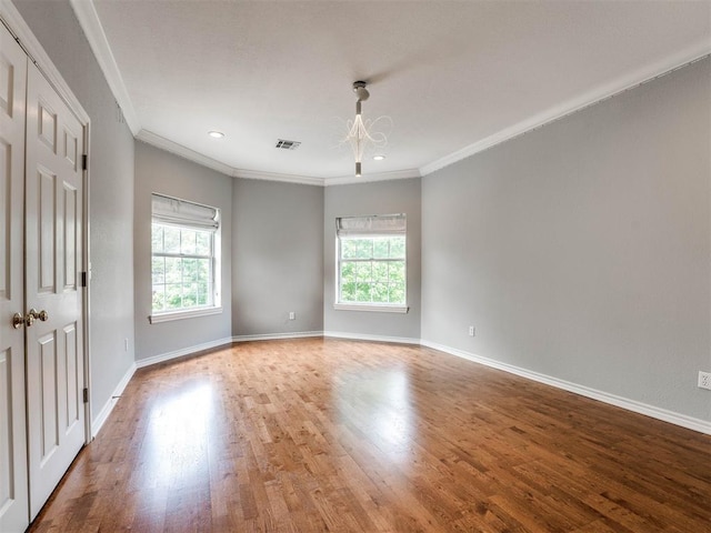 spare room featuring wood-type flooring, a wealth of natural light, and crown molding