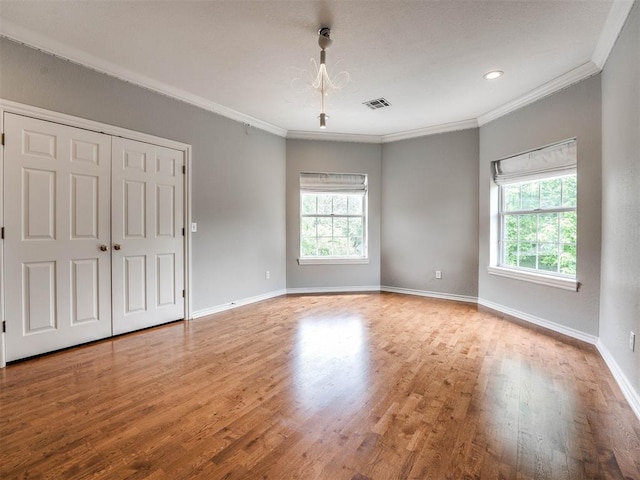 unfurnished room with crown molding, a healthy amount of sunlight, and wood-type flooring