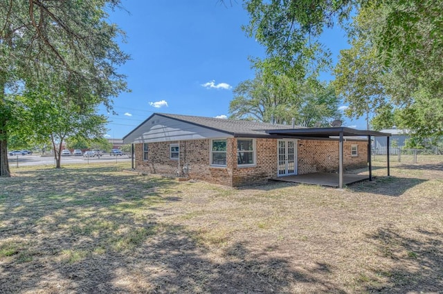 rear view of house with a lawn, french doors, and a patio