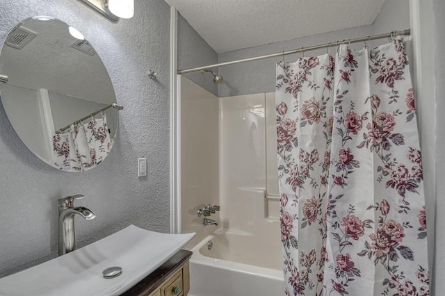 bathroom with shower / tub combo with curtain, vanity, and a textured ceiling