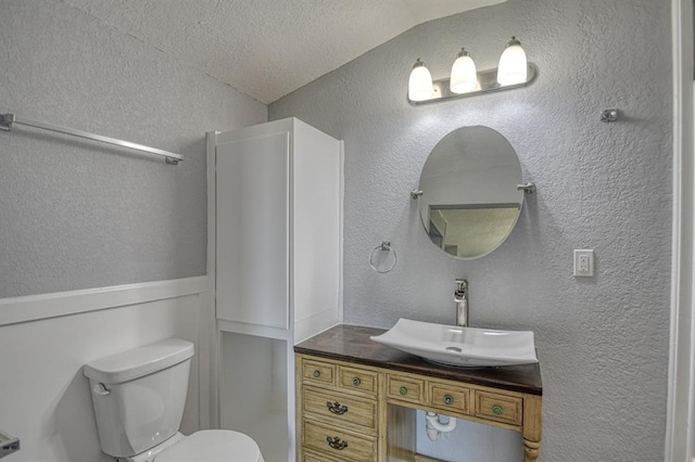 bathroom with vanity, toilet, lofted ceiling, and a textured ceiling