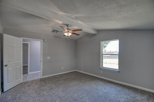 carpeted empty room featuring vaulted ceiling with beams, ceiling fan, and a textured ceiling