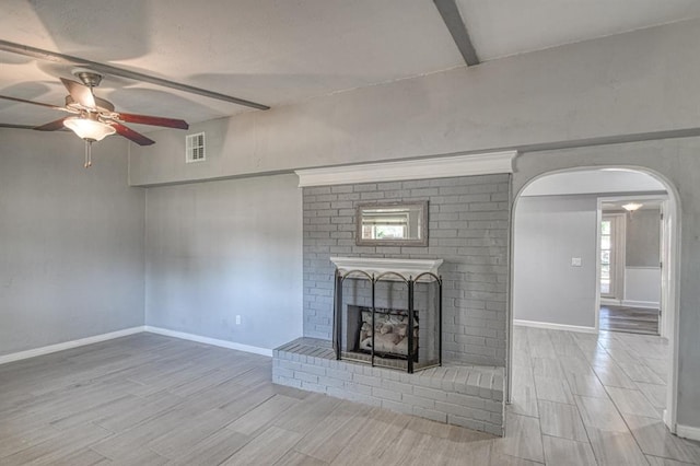 unfurnished living room with beam ceiling, a fireplace, plenty of natural light, and light hardwood / wood-style floors