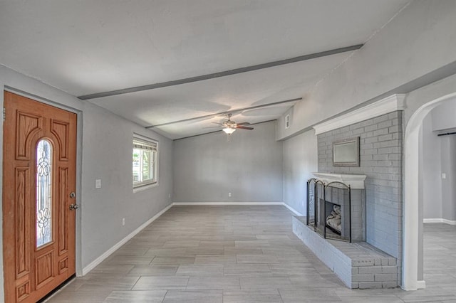 interior space with ceiling fan, a fireplace, and lofted ceiling with beams