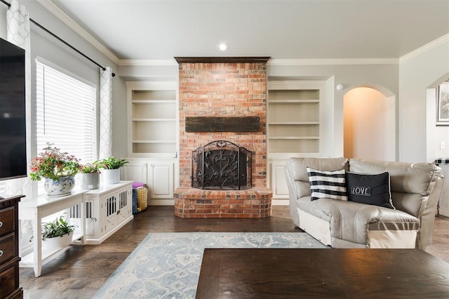 living room featuring a fireplace, ornamental molding, built in features, and dark wood-type flooring