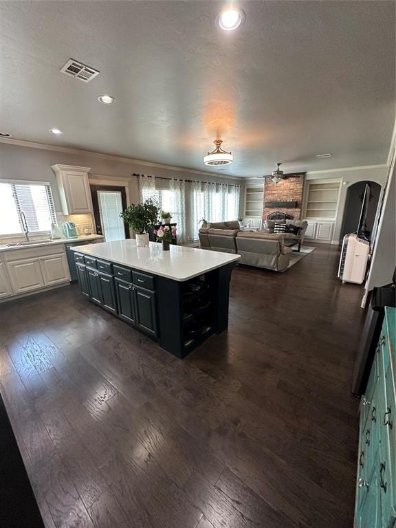 kitchen with crown molding, dark wood-type flooring, sink, a center island, and white cabinetry