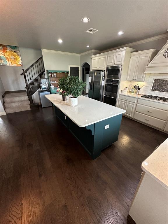 kitchen with appliances with stainless steel finishes, dark hardwood / wood-style flooring, and white cabinetry