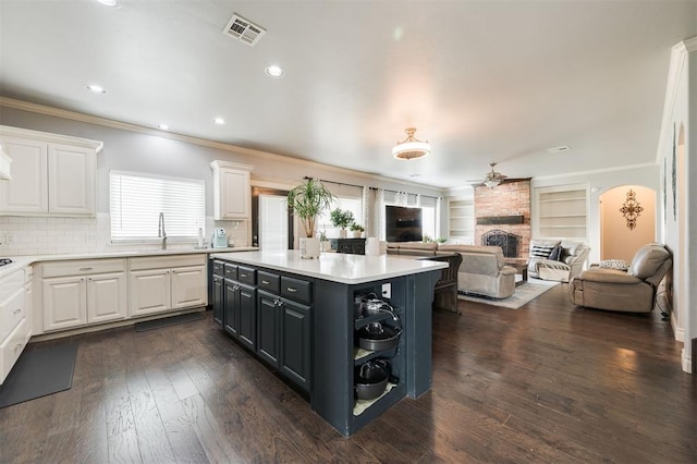 kitchen with dark wood-type flooring, white cabinetry, a kitchen island, and a stone fireplace