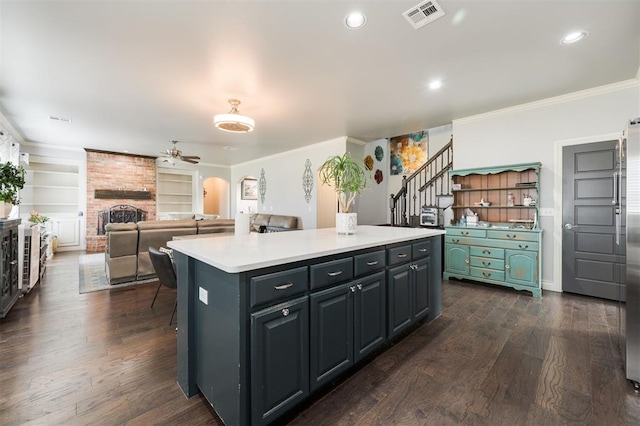 kitchen with dark hardwood / wood-style floors, a kitchen island, ornamental molding, and a fireplace