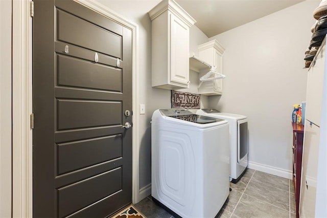 clothes washing area with cabinets, independent washer and dryer, and light tile patterned floors