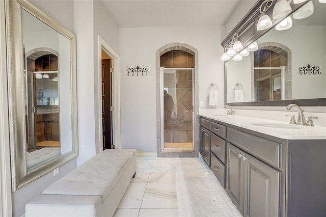 full bath with marble finish floor, a sink, a shower stall, and double vanity