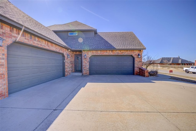 view of front facade featuring a garage, roof with shingles, driveway, and brick siding