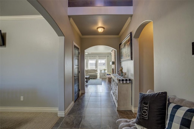 corridor with arched walkways, dark tile patterned flooring, crown molding, and baseboards