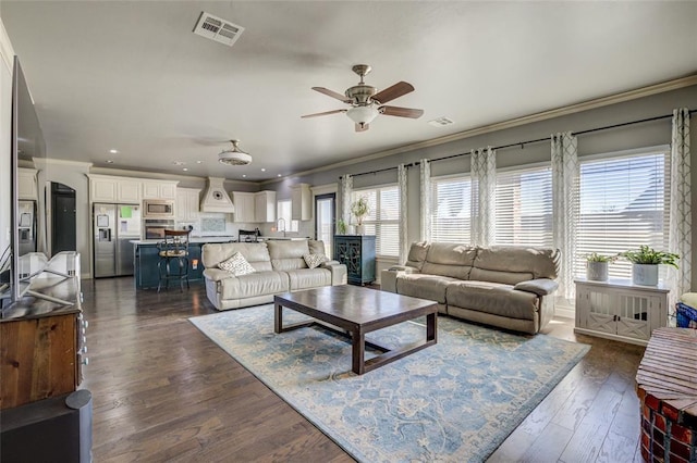 living room with arched walkways, visible vents, dark wood finished floors, and crown molding