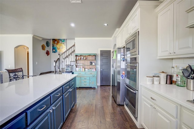 kitchen featuring appliances with stainless steel finishes, light countertops, crown molding, blue cabinetry, and white cabinetry