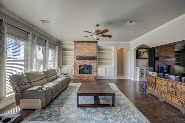 living area featuring ornamental molding, a brick fireplace, visible vents, and wood finished floors