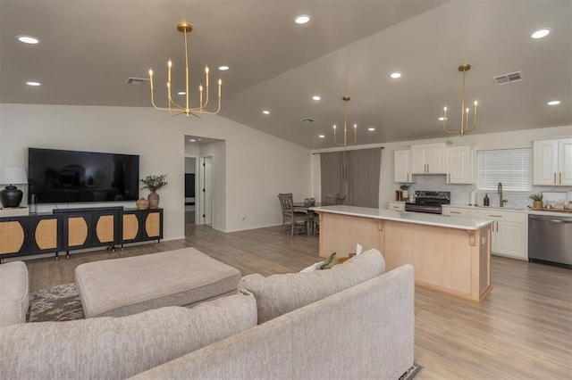 living room with light wood-type flooring, lofted ceiling, and sink