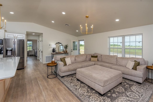 living room featuring hardwood / wood-style floors, a chandelier, and lofted ceiling