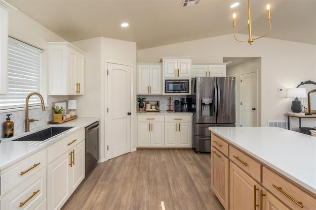 kitchen featuring backsplash, sink, vaulted ceiling, light brown cabinetry, and appliances with stainless steel finishes