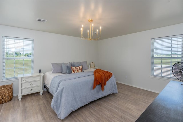 bedroom with light wood-type flooring and an inviting chandelier