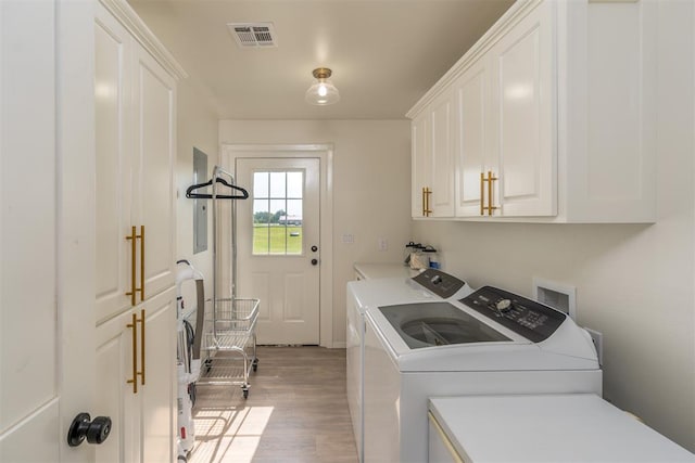 laundry room with separate washer and dryer, cabinets, and light hardwood / wood-style floors