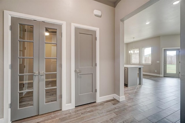 interior space with light hardwood / wood-style floors, french doors, and a chandelier