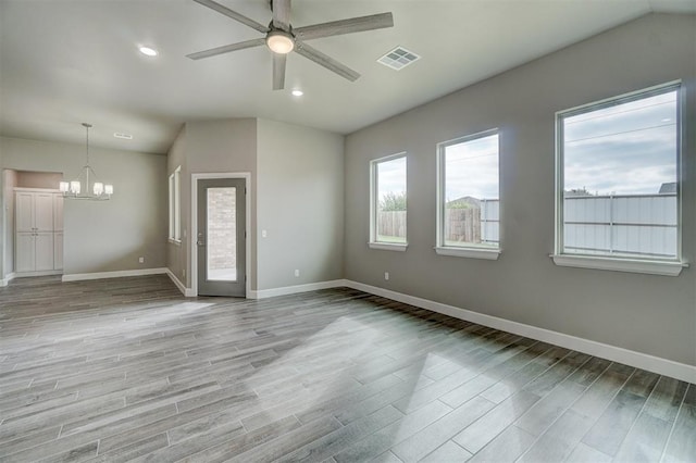 unfurnished room featuring vaulted ceiling, ceiling fan with notable chandelier, and light wood-type flooring