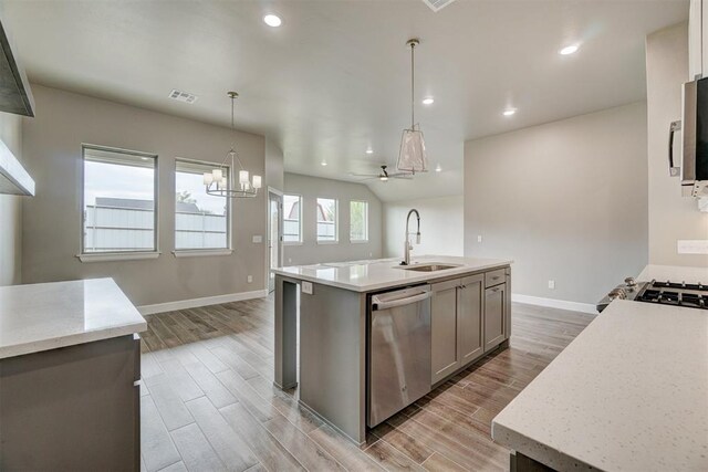 kitchen featuring sink, stainless steel appliances, light hardwood / wood-style floors, decorative light fixtures, and ceiling fan with notable chandelier