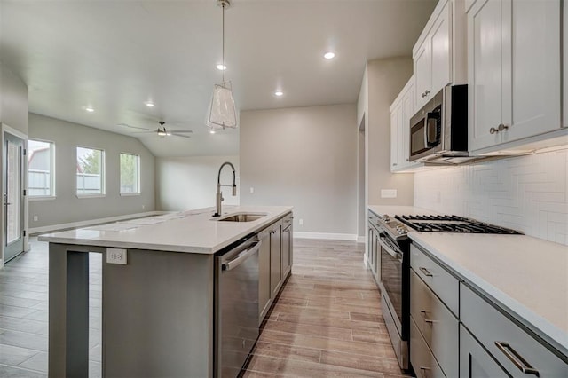 kitchen with sink, stainless steel appliances, an island with sink, light hardwood / wood-style floors, and decorative light fixtures