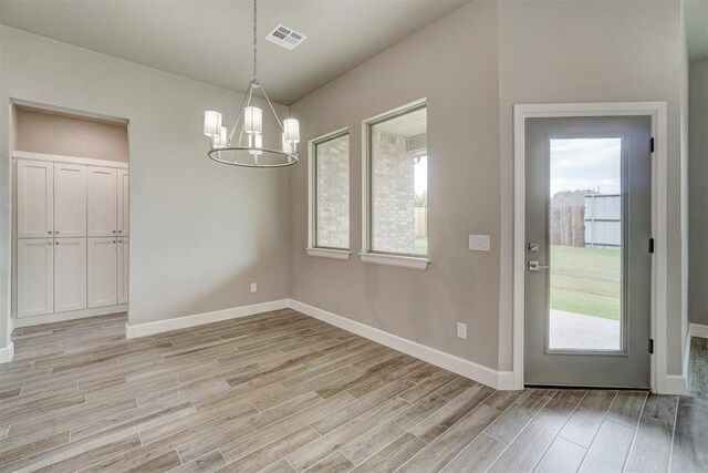 unfurnished dining area with light hardwood / wood-style floors and an inviting chandelier