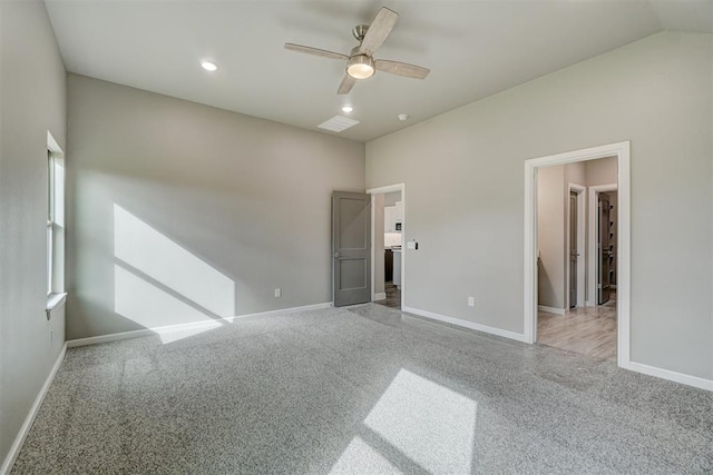 unfurnished bedroom featuring light colored carpet, a spacious closet, ceiling fan, and lofted ceiling