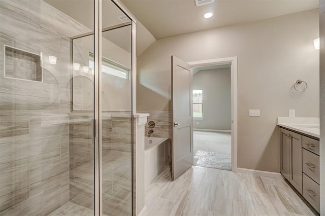 bathroom featuring vanity and independent shower and bath