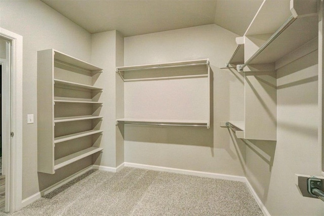 walk in closet with light carpet and lofted ceiling