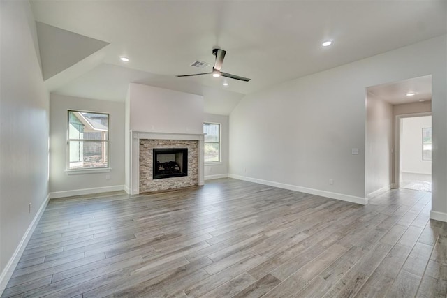 unfurnished living room featuring a fireplace, ceiling fan, plenty of natural light, and light wood-type flooring