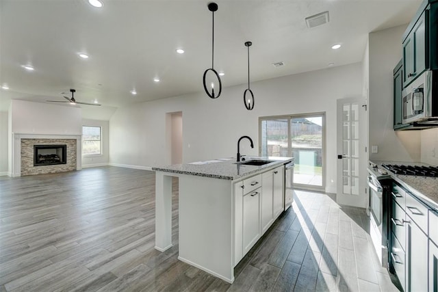 kitchen with white cabinets, sink, light hardwood / wood-style flooring, decorative light fixtures, and stainless steel appliances